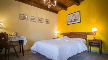 Une chambre d’hôtel avec un lit, un bureau, une chaise, une table de chevet et un lustre.