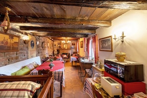 A rustic dining area with wooden beams, stone walls, and traditional decor.