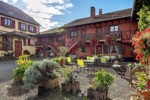A courtyard with outdoor seating, a building with a balcony, and a clear sky.