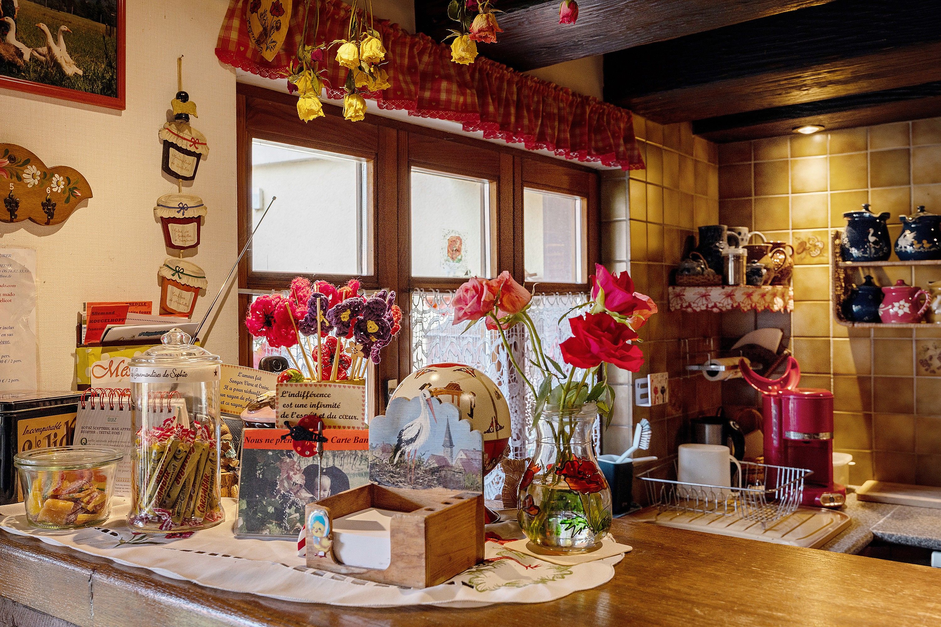 A kitchen counter with various items including jars, a vase with flowers, and kitchenware.
