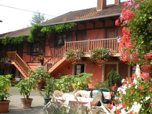 Um edifício tradicional com escadaria, plantas em vasos e área de estar externa.