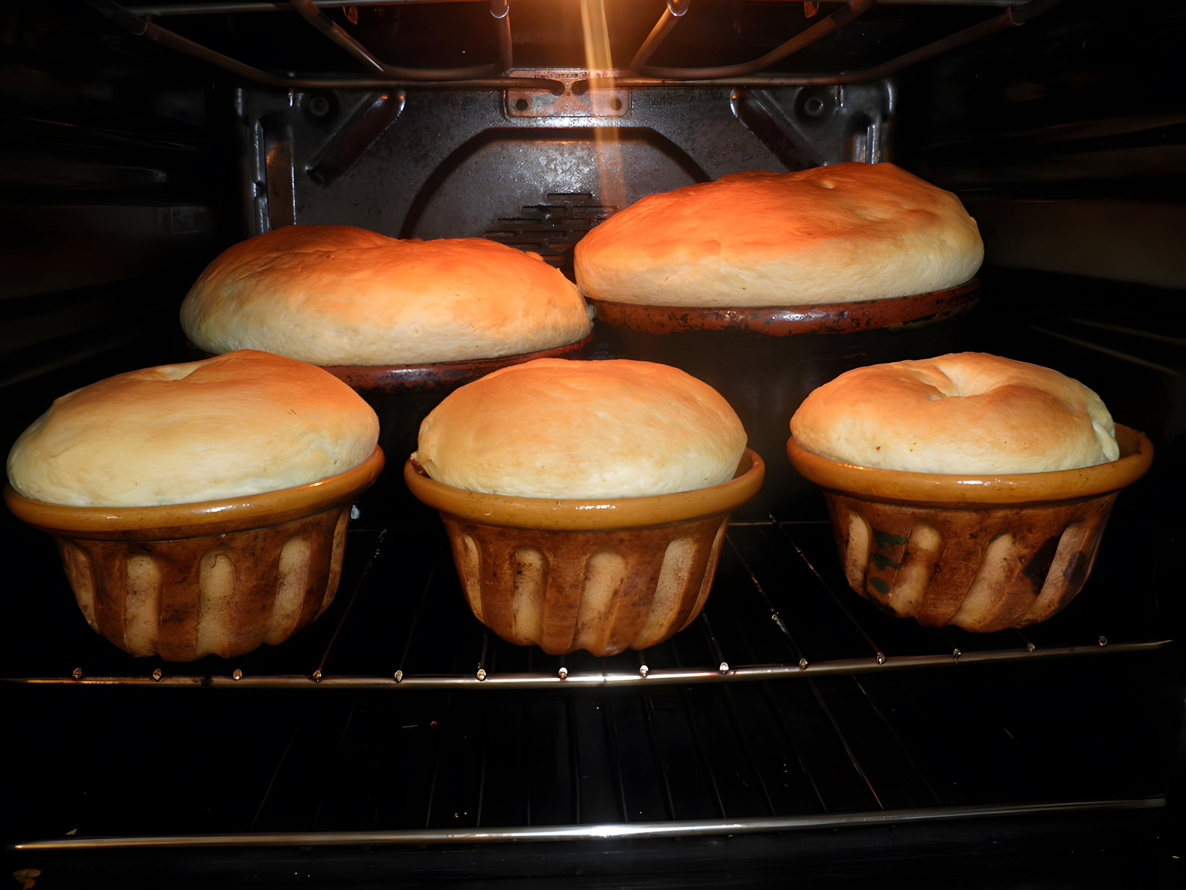 A kitchen with a baking tray containing five loaves of bread.