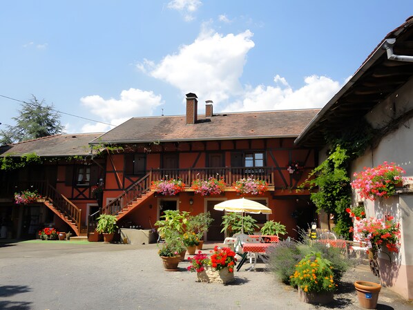 Un bâtiment traditionnel doté d’un balcon, de sièges en plein air et de plantes en pot.