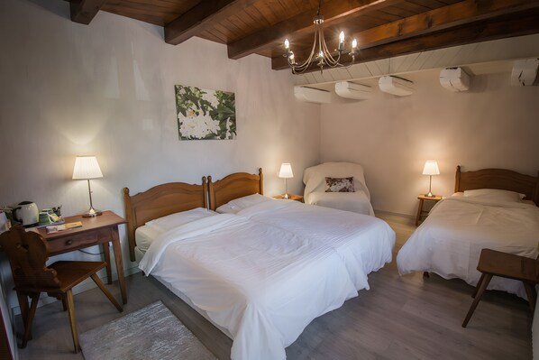 Quarto de hotel com duas camas, uma escrivaninha, uma cadeira e um candelabro.