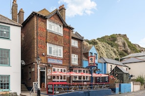 A traditional pub with a sign reading 'The Dolphin Inn' and outdoor seating with umbrellas. - Hastings Vibe | By My Getaways (Hastings)