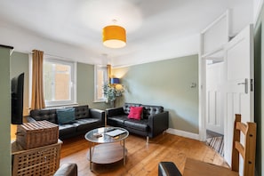 A living room with a sofa, a coffee table, a television, and a lamp. - Hastings Vibe | By My Getaways (Hastings)