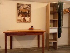 A room with a wooden table, a shelf unit, and a painting on the wall.
