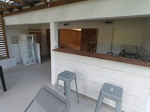A kitchen area with a wooden countertop, two stools, a sink, and a door leading to another room.