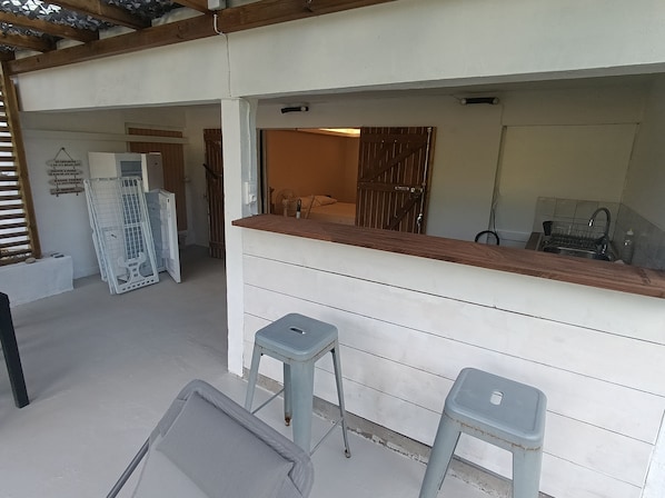 A kitchen area with a wooden countertop, two stools, a sink, and a door leading to another room.