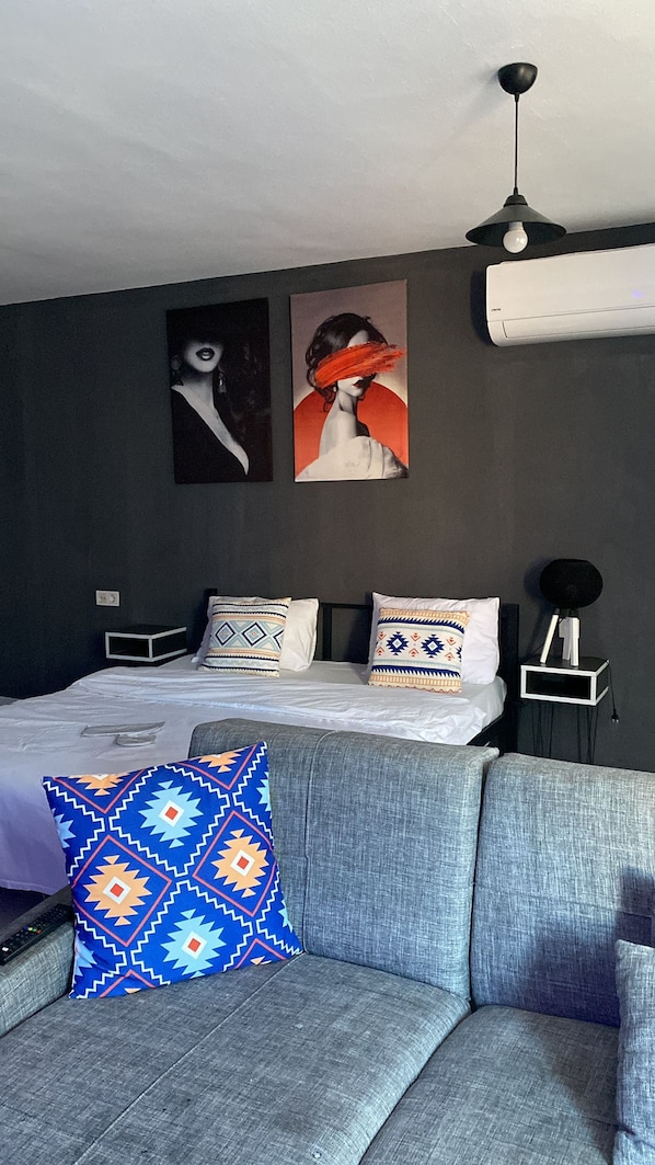 Un dormitorio moderno con una cama, un sofá y dos obras de arte colgadas en la pared.