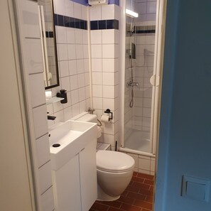 Ein Badezimmer mit weißem Waschbecken, WC und Duschbereich.