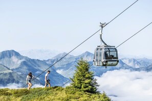 A cable car in a mountainous area with two people walking beside it. - Apartment 'Waldtraum - Waldflüstern' with Mountain View, Terrace, Opening December 2026 (Au)