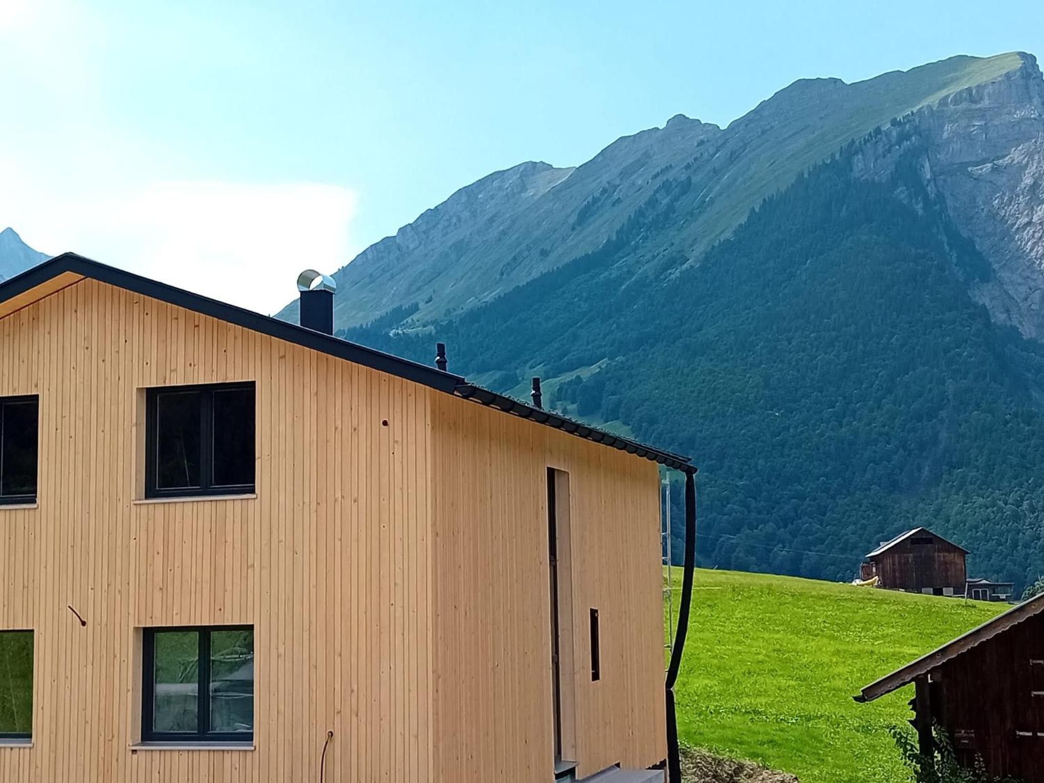 Un edificio de madera con varias ventanas y una puerta, frente a un paisaje montañoso.