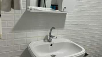 Un baño con lavamanos blanco, un espejo encima y un inodoro.