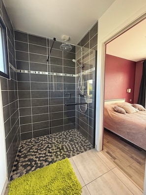 A modern bathroom with a shower, tiled walls, and a visible window. - Vrbo Property (Landéda)