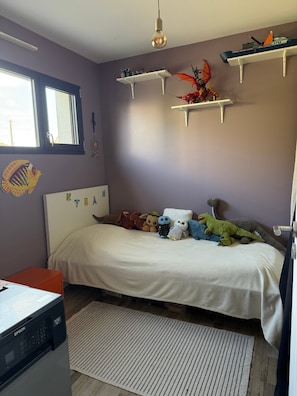 A bedroom with a bed, a desk, and shelves with toys. - Casa Isann—Pool—Ocean View & GR34 (Landéda)
