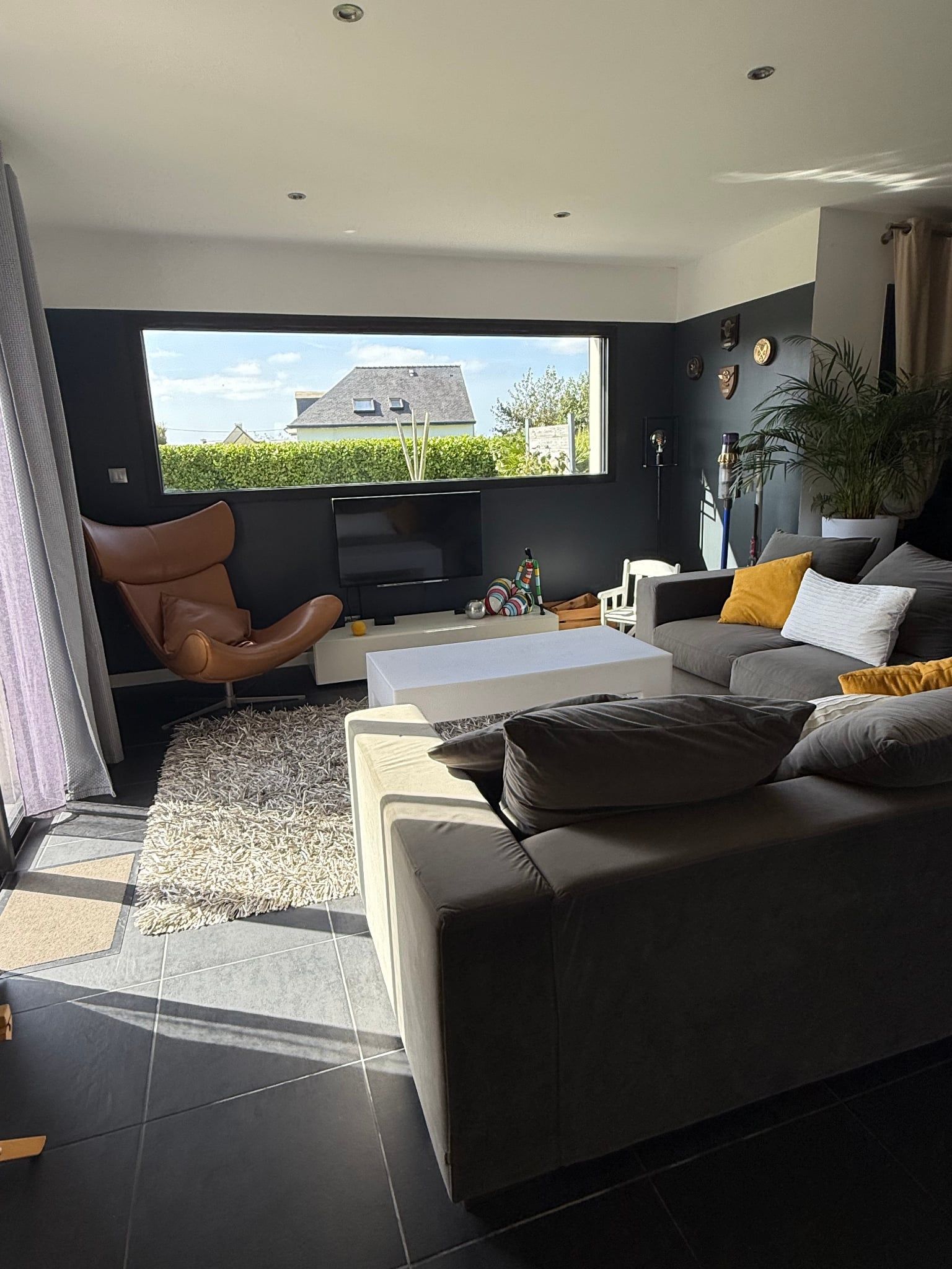 Un salon moderne avec un canapé, un fauteuil et un téléviseur.
