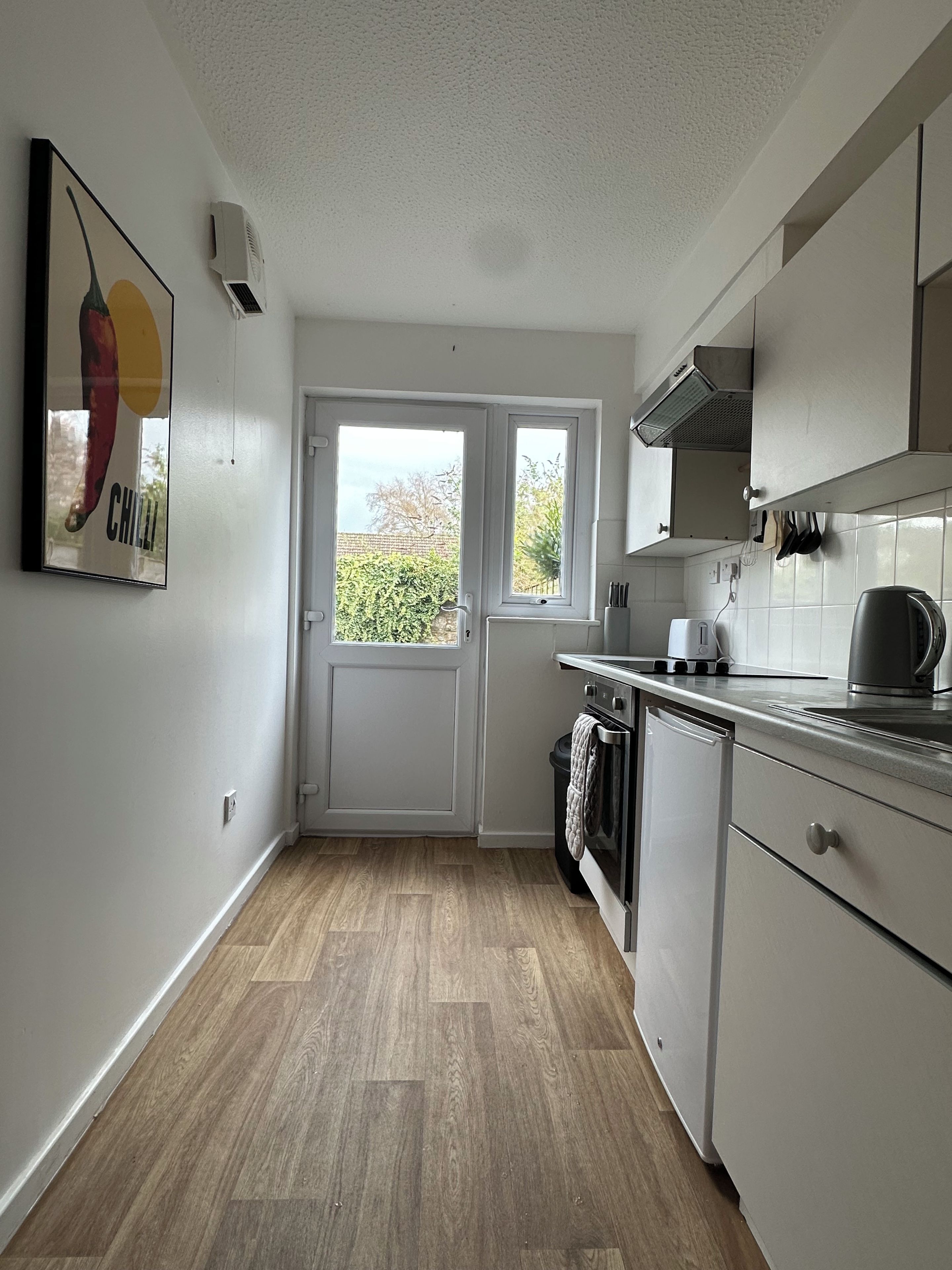 A kitchen with a double door, a window, and a wall-mounted air conditioner.