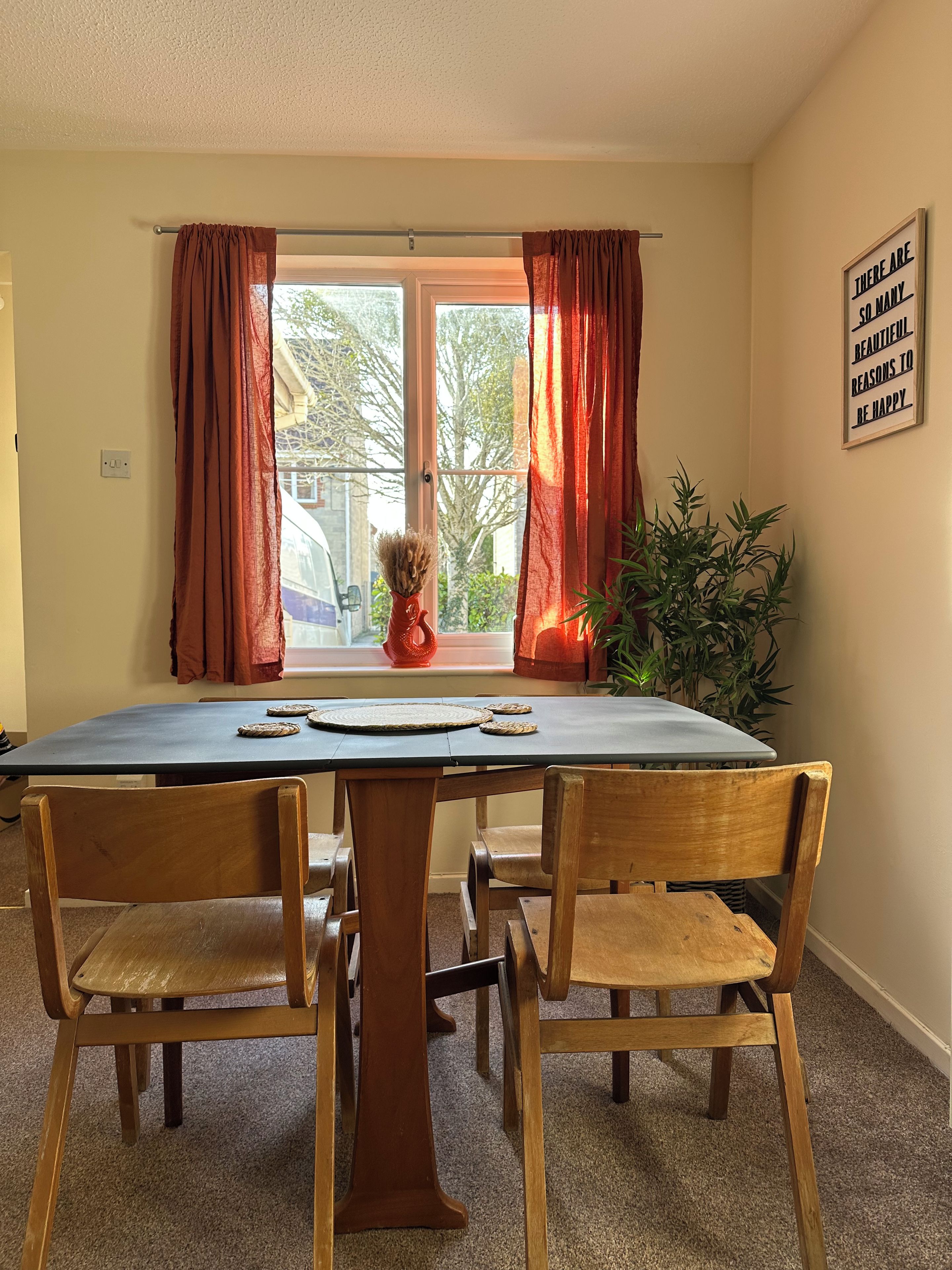 A dining area with a table, chairs, and a window with curtains.
