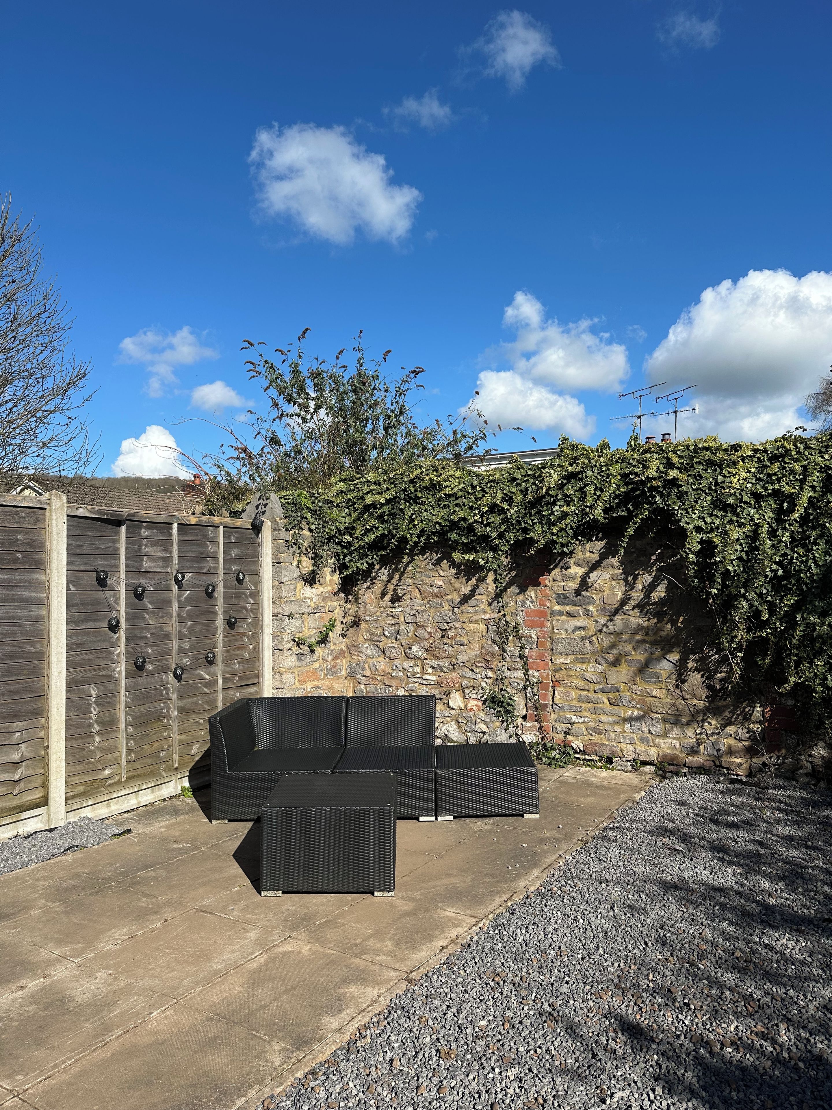 A patio area with outdoor furniture and a stone wall.
