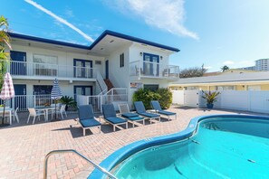 Un hôtel doté d’une piscine, de chaises longues et d’un escalier menant au balcon.