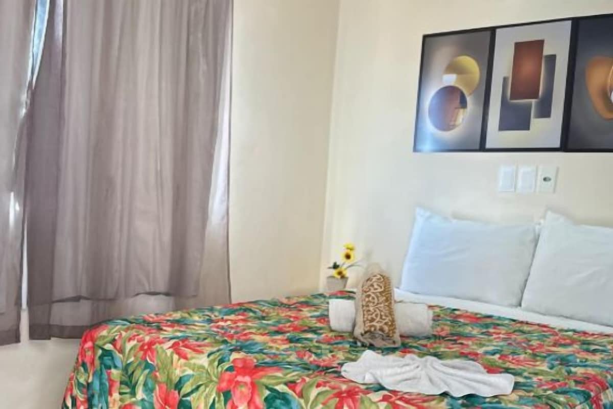 Una habitación de hotel con una cama, cortinas, una mesita de noche y decoración en la pared.