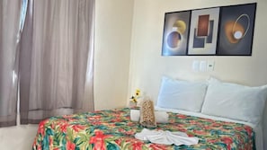 Una habitación de hotel con una cama, cortinas, una mesita de noche y decoración en la pared.