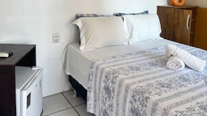 Una cama individual con un edredón estampado, un armario de madera y un pequeño escritorio con silla.
