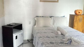 Un dormitorio con una cama, un armario de madera y un pequeño electrodoméstico blanco.