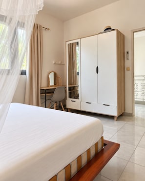 A bedroom with a bed, a desk, a wardrobe, and a balcony. - House + apartment, tropical garden, terrace, and game room, 5 minutes from the beaches (Rivière-Pilote)