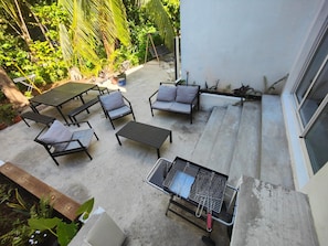 An outdoor patio with a table and chairs, a grill, and a small garden area. - House + apartment, tropical garden, terrace, and game room, 5 minutes from the beaches (Rivière-Pilote)