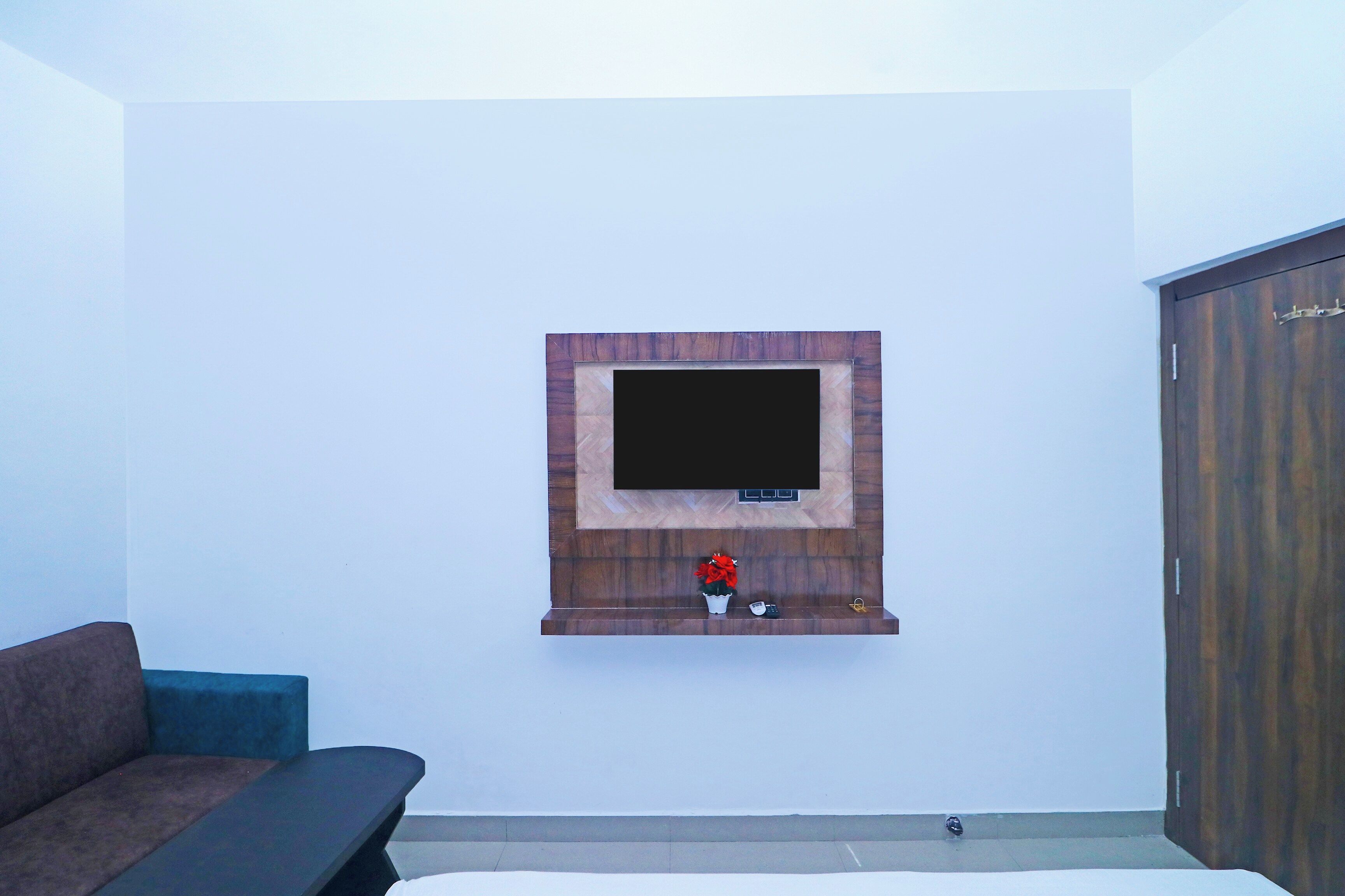 Una habitación con una televisión montada en una pared de madera, un sofá y un armario.