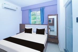 Un dormitorio con cama, armario, ventana con cortinas y equipo de aire acondicionado.