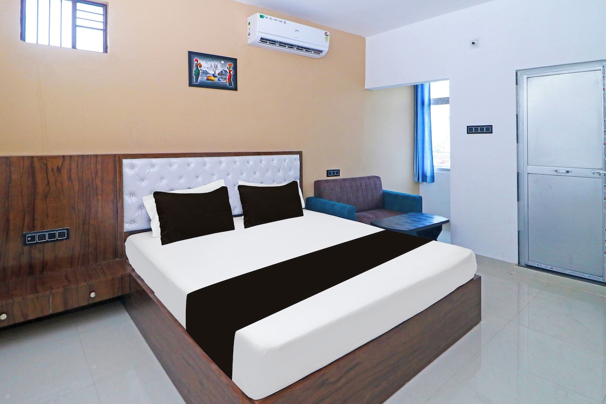 Una habitación de hotel moderna con una cama grande, un sofá, una mesita y un armario.
