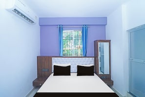 Un dormitorio con cama, armario y ventana con cortinas.