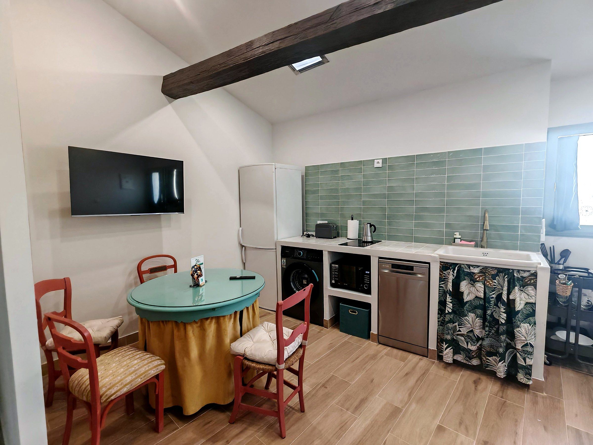 A compact kitchen with a dining area, a flat-screen TV, and a microwave.