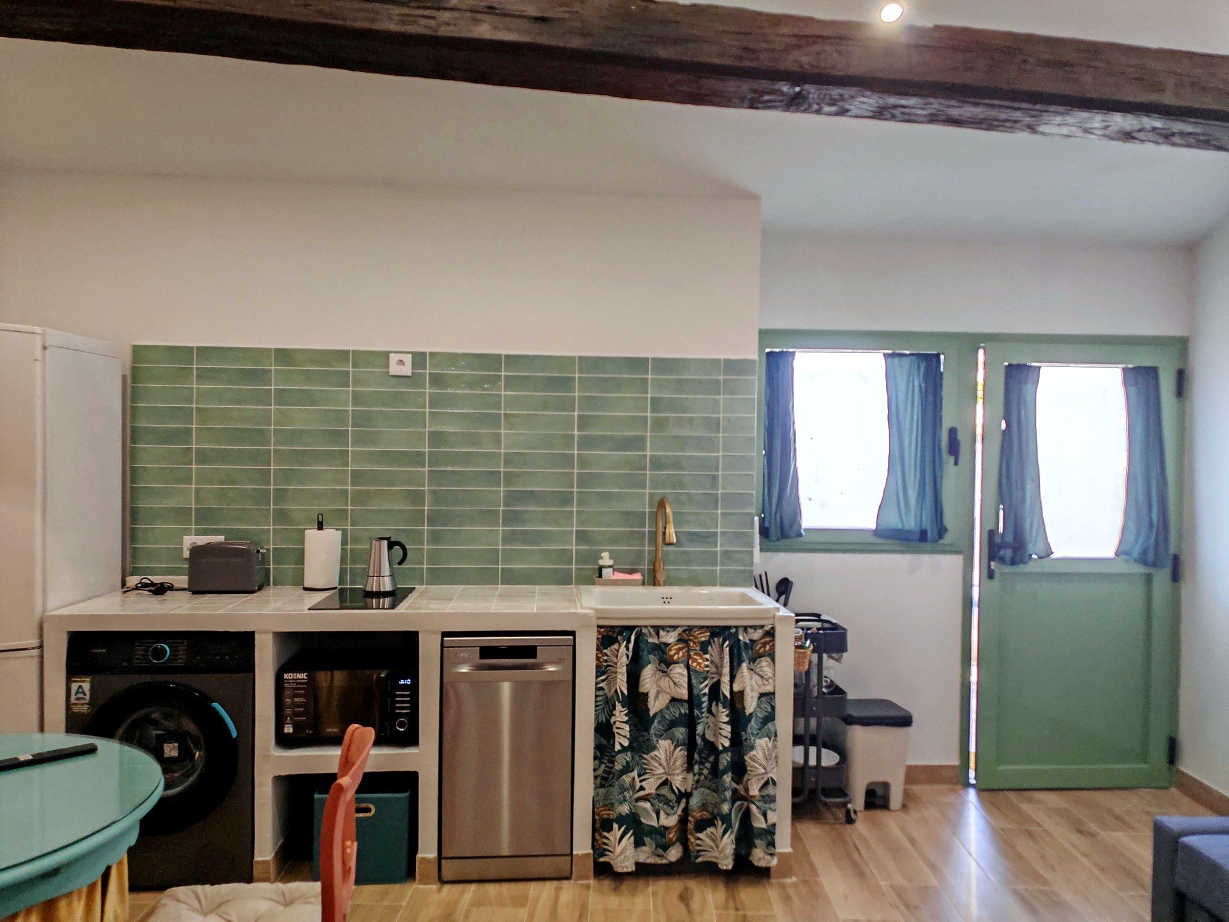 A compact kitchen with a washing machine, dishwasher, microwave, and a small sink.
