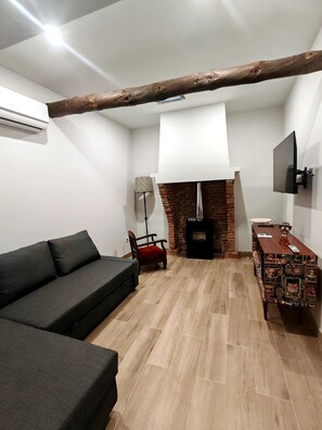 A modern living room with a sofa, a red chair, a TV, a fireplace, and a wooden beam ceiling. - Villa Margarolo by gaiarooms (Morille)
