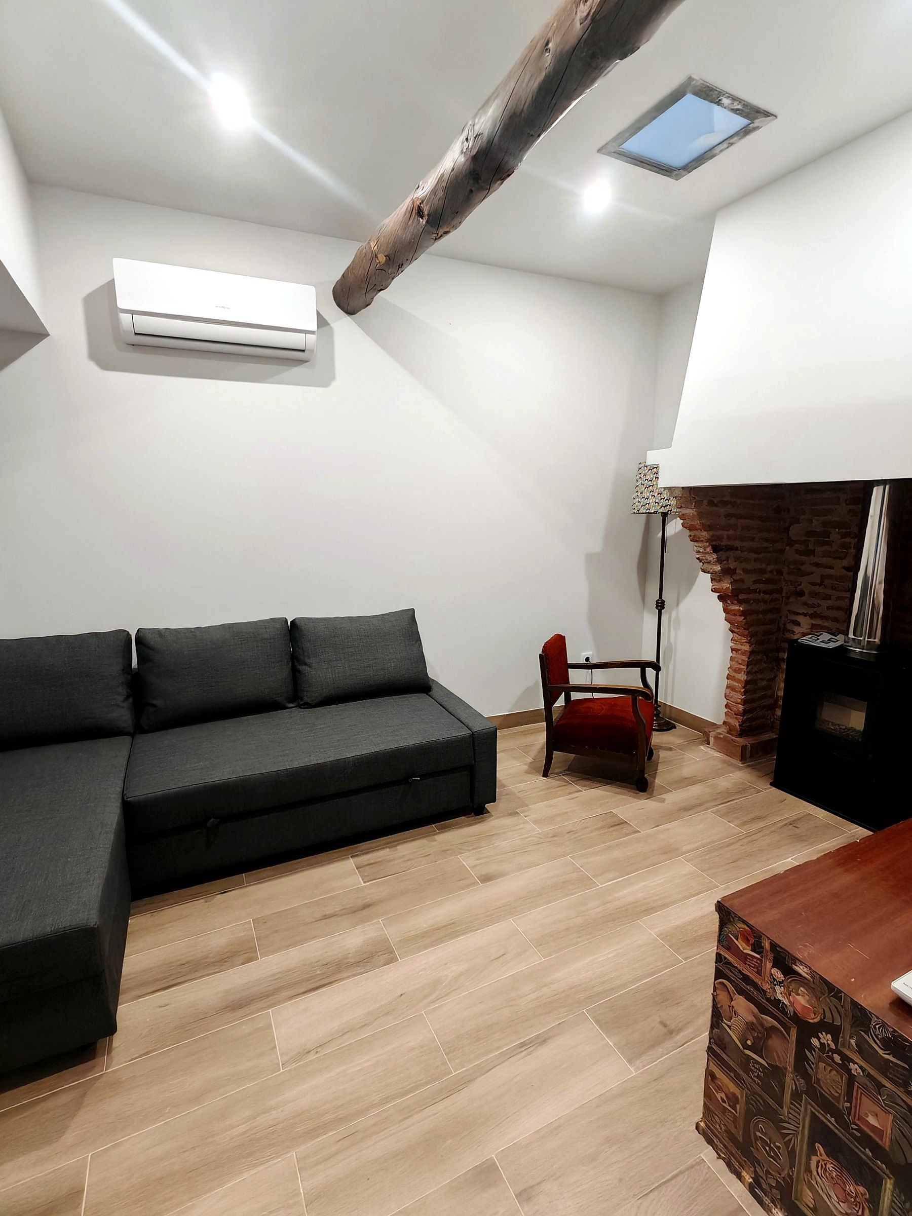 Una sala moderna con un sofá seccional, una chimenea y un techo inclinado con tragaluces.