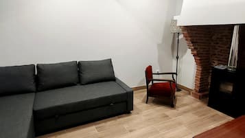 Una sala moderna con un sofá seccional, una chimenea y un techo inclinado con tragaluces.