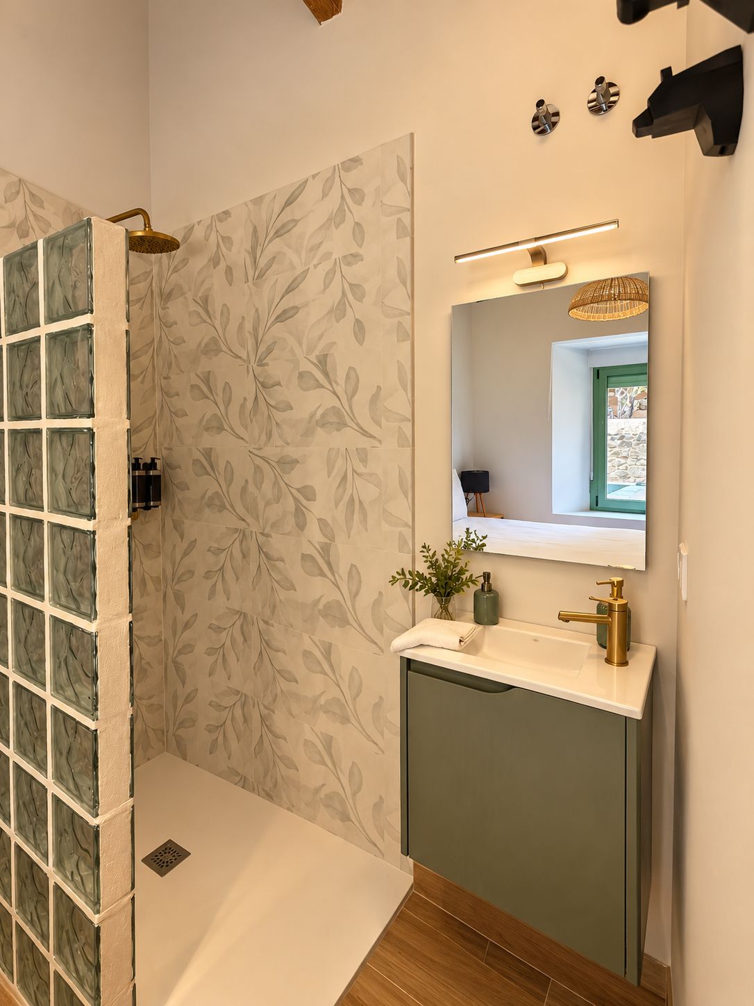 A bathroom with a shower, a sink with a mirror, and a decorative wall.
