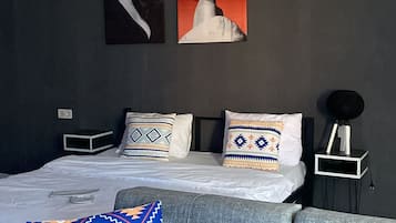 Un dormitorio moderno con una cama, un sofá y dos obras de arte colgadas en la pared.