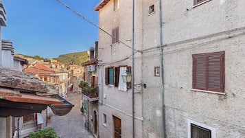 A narrow street with buildings on either side, featuring traditional architecture with visible balconies and windows.