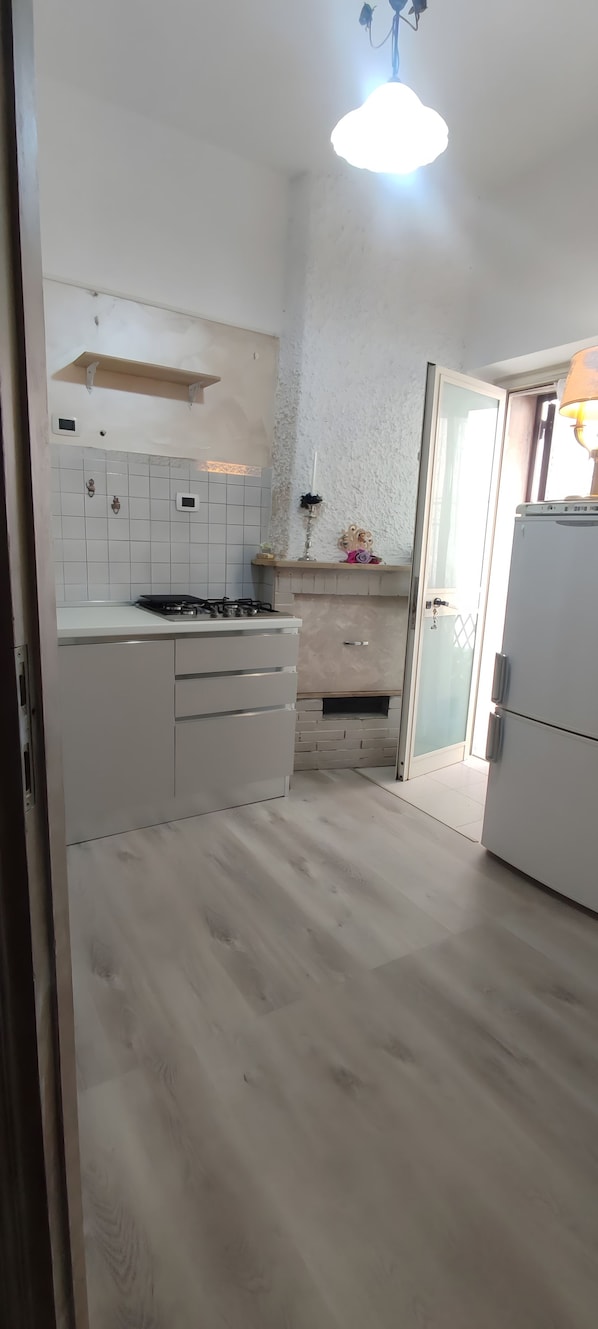 A kitchen with a gas stove, white cabinets, a tiled backsplash, and a hanging light fixture.