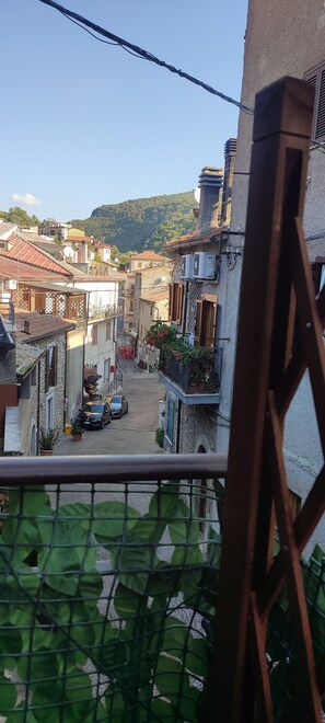 Un quartiere residenziale con edifici in pietra, una strada stretta e vista su una collina.