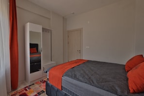 A bedroom with a bed, a wardrobe, a door, and a rug. - H&M SUIT CAPPADOCIA (Merkez)