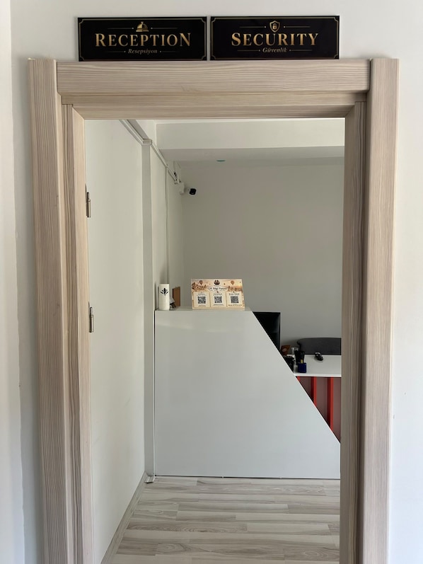Zona de recepción con mostrador de recepción, mesa de seguridad y un cartel en la pared que indica la ubicación de cada servicio.