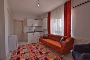 A compact living space with a kitchenette, a sofa, and a patterned rug. - H&M SUIT CAPPADOCIA (Merkez)