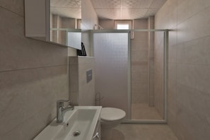 A modern bathroom with a glass shower enclosure, a white sink, and a toilet. - H&M SUIT CAPPADOCIA (Merkez)