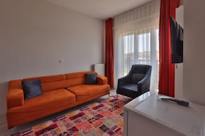 A room with a sofa, a chair, a television, and a patterned rug. - H&M SUIT CAPPADOCIA (Merkez)